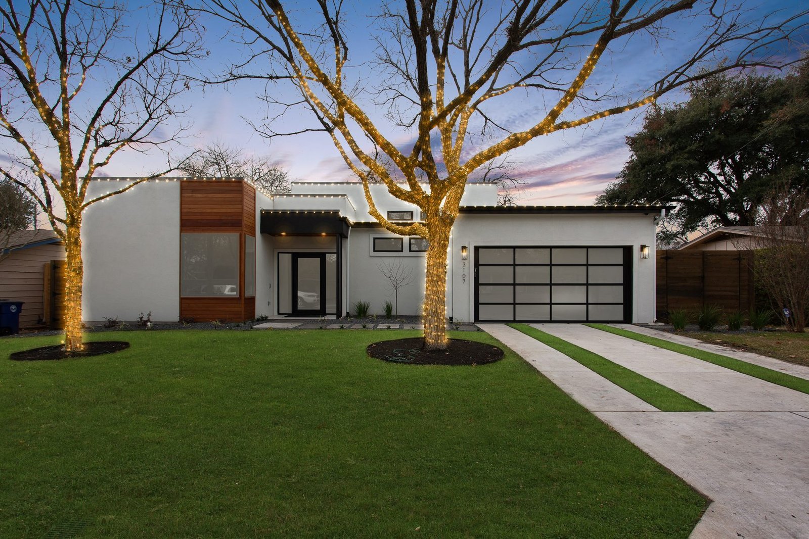 Modern Hill Country home exterior at dusk with lit trees