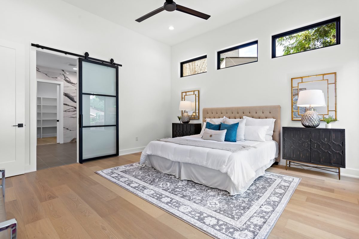 Primary bedroom with tufted headboard and sliding glass door
